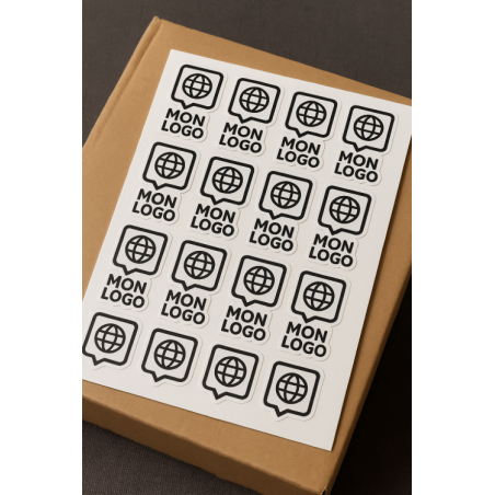 Planche d’autocollants personnalisés logo posée sur boîte en carton kraft – impression professionnelle vinyle